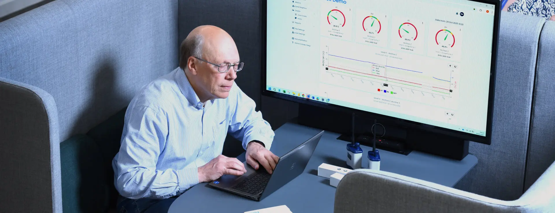 A facilities manager reviewing live Darca Command dashboards on screen, with Eltek wireless transmitters on the desk