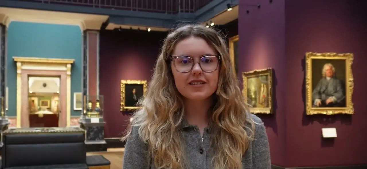 A preventive conservator in a picture gallery at the Fitzwilliam Museum, Cambridge, hung with framed paintings whose temperature, humidity and light Eltek monitoring helps protect