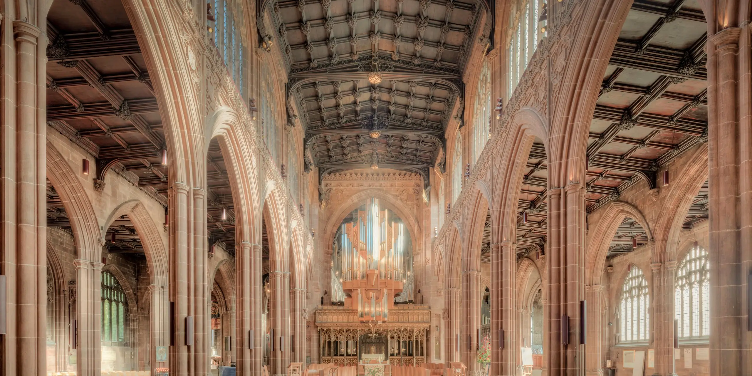 The vaulted nave of a historic cathedral, its sandstone arches and timber roof rising above the choir and organ, the kind of listed heritage building where Eltek monitors temperature, humidity and light without cabling through protected fabric