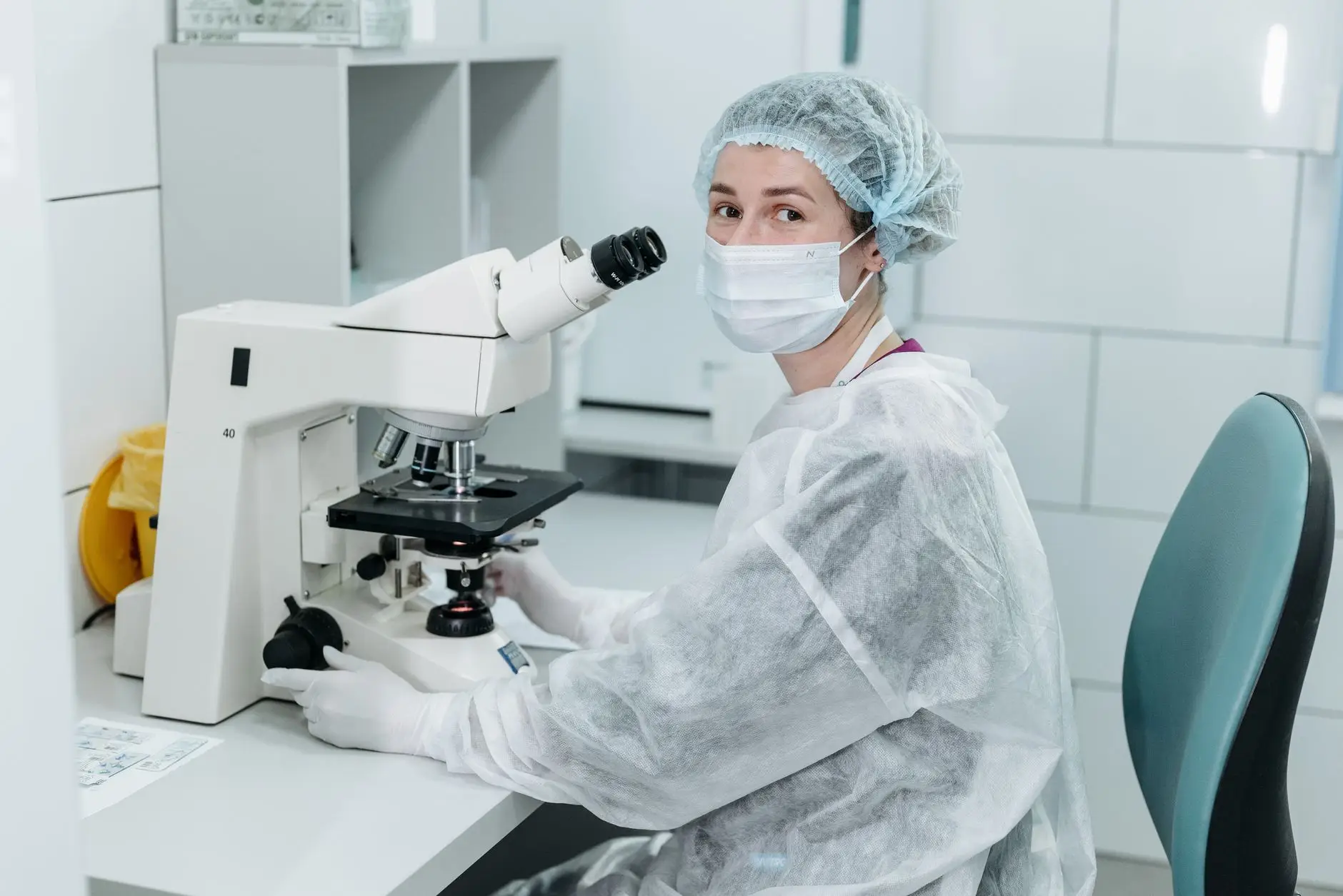 An embryologist working at a microscope in a fertility laboratory, the kind of environment where Eltek monitors incubators and cryogenic storage that irreplaceable samples depend on