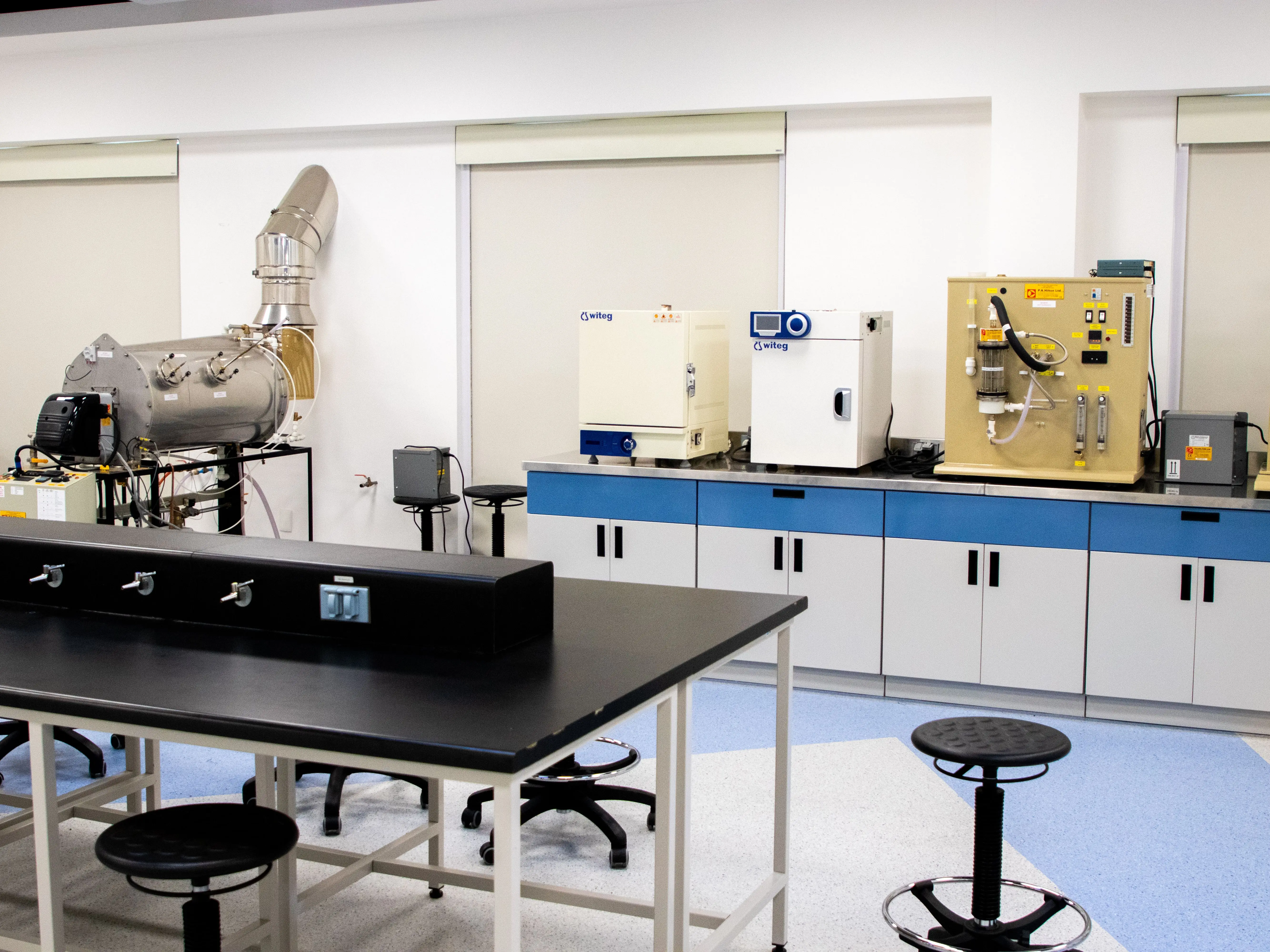 A life-science laboratory bench lined with benchtop environmental chambers, an oven and an incubator, the kind of energy-intensive equipment monitored for both efficiency and sample protection.