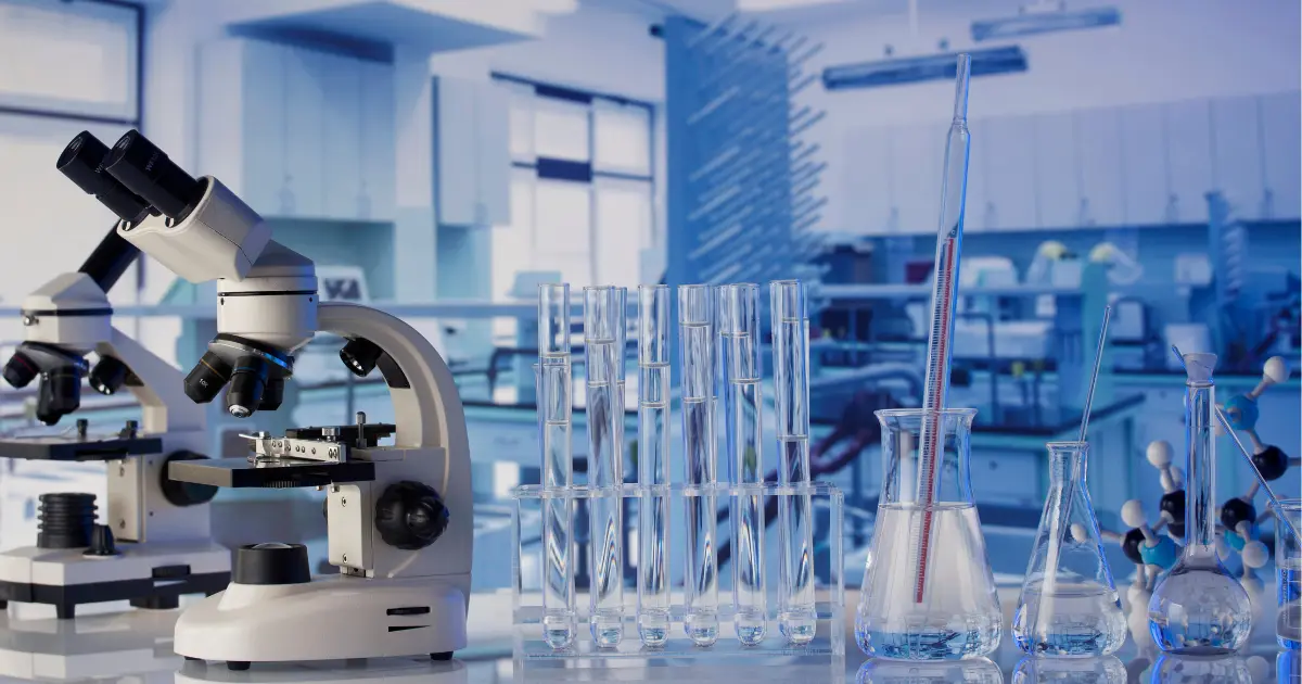A clean, bright, clinical life-science laboratory with a microscope and sample glassware, the kind of regulated environment Eltek monitors continuously for temperature, humidity and compliance