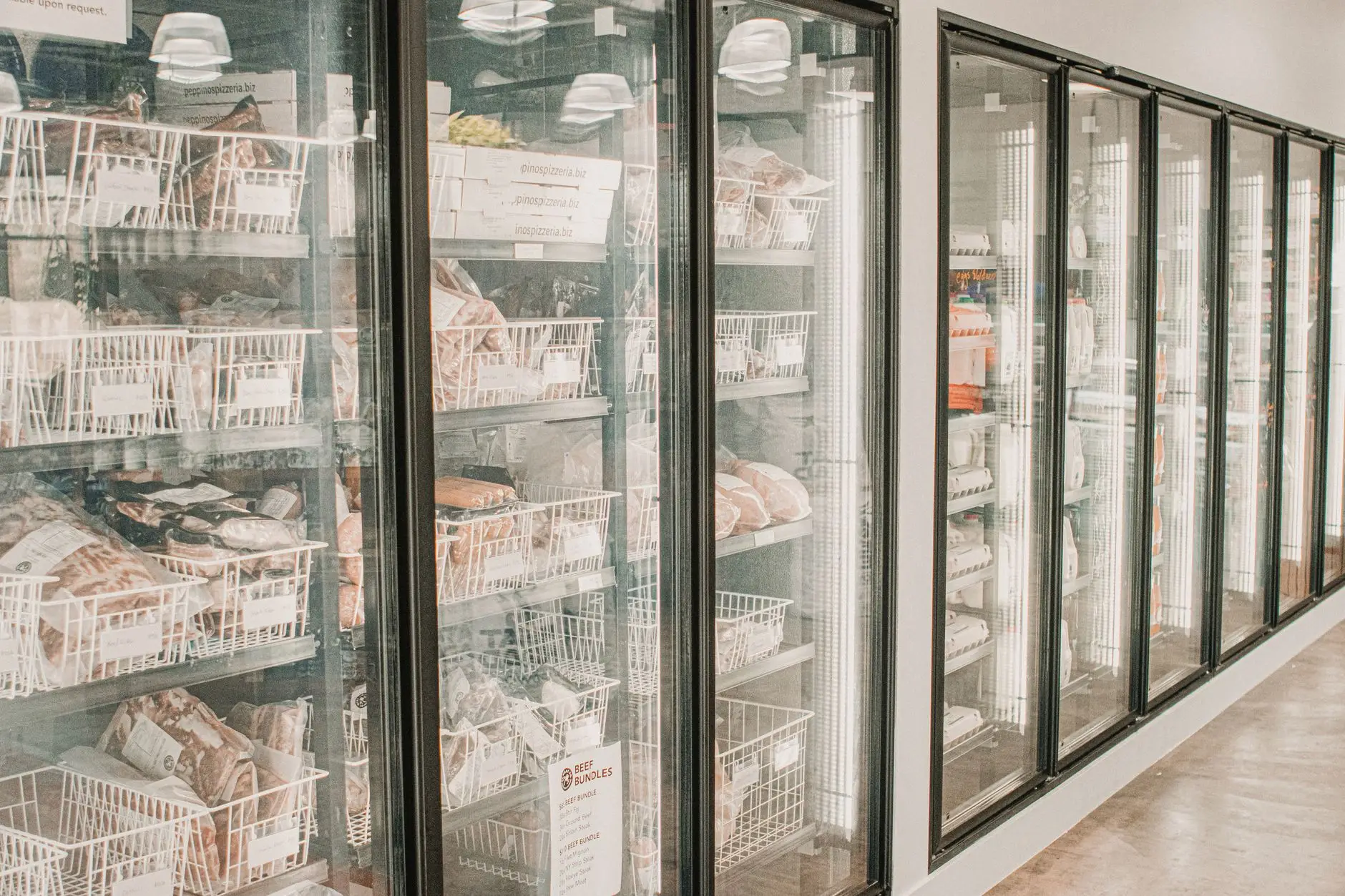 A retail cold-storage freezer aisle with frozen food behind glass doors, the kind of food-retail cold-chain environment Eltek monitors continuously