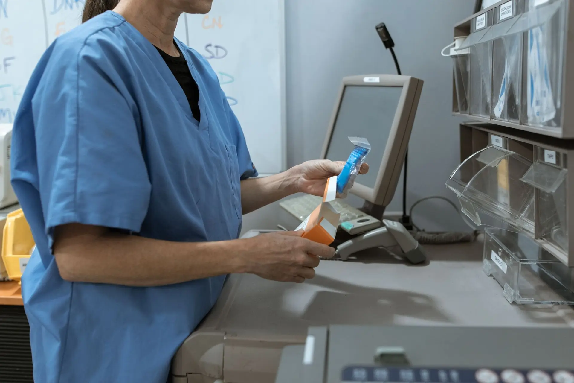 A gloved laboratory worker checking vials in a temperature-controlled refrigerator used for regulated cold storage